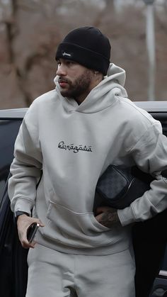 a man in white sweatpants and a black hat is getting out of a car