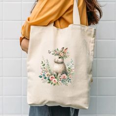 Add a touch of nature to your everyday style with our Eco-Friendly Reusable Tote Bag, featuring rabbit with flower print. Made from 100% organic cotton, this durable tote is perfect for grocery shopping, carrying books, or as a stylish accessory for a day out. The vibrant, nature-inspired design not only makes a fashion statement but also supports a sustainable lifestyle. Highlights Designed by EcoIstas Collection Materials: Primary fabric type: Canvas; Secondary fabric type: Cotton ⭐About -100% Eco-friendly Natural Canvas Bag For Spring, Eco-friendly Cream Canvas Bag As Gift, Eco-friendly Cream Canvas Bag For Gifts, Eco-friendly Beige Shoulder Bag For Gift, Eco-friendly Cream Canvas Bag Gift, Spring Gift Shoulder Bag In Natural Color, Handmade Nature-inspired Bag For Daily Use, Natural Shoulder Bag As Spring Gift, White Botanical Rectangular Bag