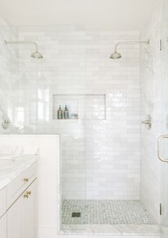 a white bathroom with marble counter tops and tile flooring, along with a walk in shower