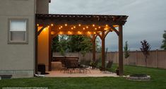 an outdoor patio with string lights on the pergolated area and grill in the back yard