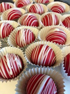 chocolates with red and white stripes are lined up in paper cups on a table