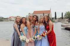 a group of young women standing next to each other in front of a body of water