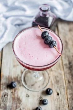 a pink drink with blueberries on the rim