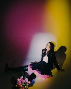 a woman sitting on the ground with flowers in front of her