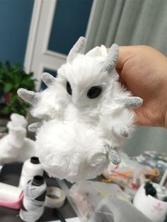 a hand holding a white stuffed animal with horns