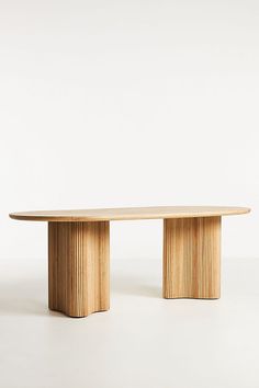 an oval wooden table sitting on top of a white floor