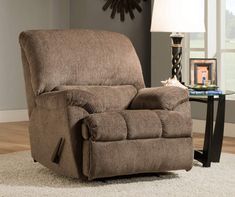 a living room with a brown recliner and a clock on the wall behind it