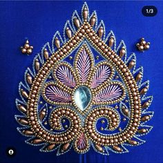 an intricately designed brooch with pearls and beads on a blue background is shown