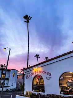 the exterior of burgers and shakes with palm trees in the background at sunset or dawn