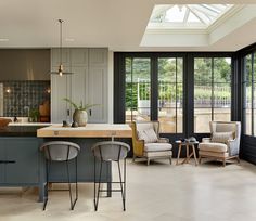 a kitchen with two chairs and an island in the middle, surrounded by glass doors