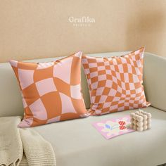 two orange and white pillows sitting on top of a couch next to a pillow case