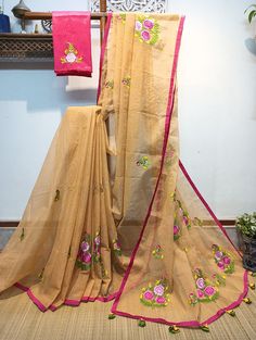 Exquisite embroidery work in floral design has been neatly and densely done on a sandalwood color Resham check saree. Here we have used multicolor Resham thread and shaded embroidery technic (Minakari work).  Two different sizes of floral designs are spread all over the saree. This saree is framed with a rani pink color border accessorized with handmade tassels. This saree comes with a hand embroidered contrast blouse piece. This saree is summer-friendly and very comfortable to wear. Details: *Blouse: With Hand Embroidered Blouse Piece *Fabric: Handloom Resham check saree *Work: Machine Embroidery work  this work is neither Computerized Machine Embroidery work nor machine Aari Embroidery with woolen thread. * Its completely Manual Machine Embroidery Work with silk threads..] *Saree length: Beige Bollywood Saree With Resham Embroidery, Semi-stitched Chanderi Saree In Beige, Semi-stitched Beige Chanderi Saree, Beige Semi-stitched Chanderi Saree, Embroidered Beige Saree In Traditional Drape, Traditional Embroidered Beige Saree, Bollywood Style Embroidered Beige Saree, Embroidered Beige Saree For Festivals, Festive Embroidered Beige Saree