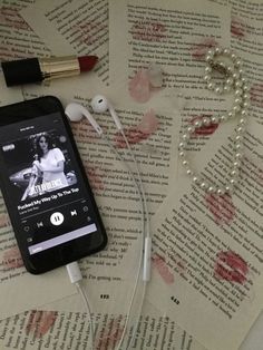 an mp3 player with ear buds and headphones on top of a book that is covered in pink flowers