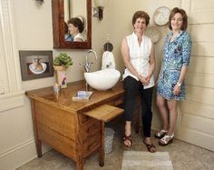 two women standing next to each other in front of a bathroom sink and vanity area