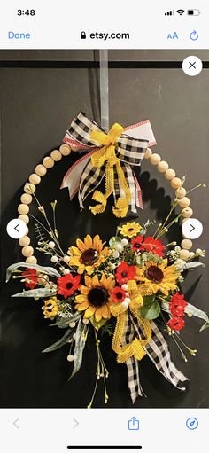 a wreath with sunflowers and other flowers hanging on a door