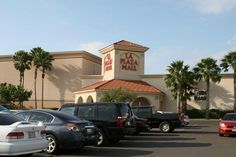 several cars parked in front of a pizza hut with palm trees behind it and the building across the street