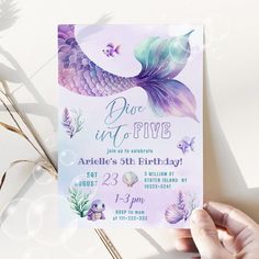 a hand holding up a purple and blue mermaid birthday party card with fish on it