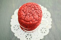 two red cookies sitting on top of a white doily