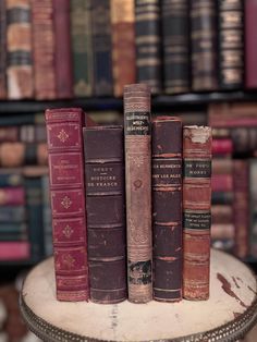 three old books are stacked on top of each other in front of a bookcase