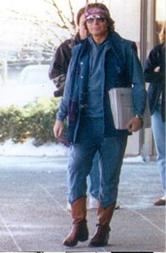 an old photo of a man walking down the street wearing cowboy boots and holding a binder