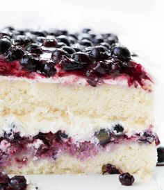 a close up of a piece of cake with blueberries and cream filling on it