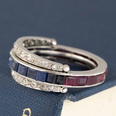 Another one of our personal faves, and a style which sells out almost immediately - the flip ring! Popular during the art deco era, they always feature a combination of gemstones and diamonds, with part of the ring "flipping" between 2 different sections to give the illusion of different bands being stacked together. With this band, you have the diamond band flipping between a blue sapphire section and a ruby section. Its literally 2 bands in one - you can't tell me that that's NOT fun and uniqi Art Deco Multi-stone Diamond Ring, Art Deco Multi-stone Platinum Diamond Ring, Art Deco Sapphire Ring With Accent Stones, Art Deco Rings With Accent Stones, Art Deco Multi-stone Rings For Anniversary, Art Deco Platinum Multi-stone Rings, Platinum Multi-stone Art Deco Rings, Art Deco Multi-stone Anniversary Rings, Art Deco Multi-stone Platinum Rings