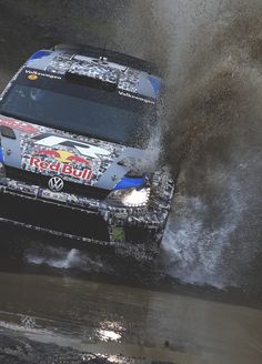 a car is driving through some water on a dirt track with splashing from its tires