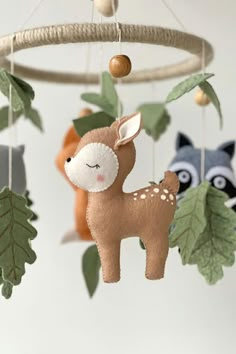 an animal mobile hanging from a tree with leaves and other animals on it's sides