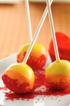 three candy apples are sitting on a white plate with red sprinkles around them