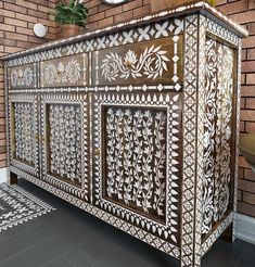 an intricately designed cabinet is shown against a brick wall