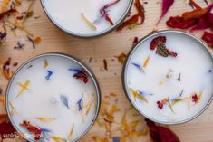 three tins filled with different types of flowers on top of a wooden table next to leaves