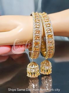 Champage Jumki Bangle- Gold Cz Bangles - Handmade Cz Bracelet- Indian Bangle- AD Jhoomar Bangle- Cz Kangan Set- Cooriyaan- Hanging Bangles  SAME DAY Ship from USA- oder before 1 pm. Handmade with Care. ◾ One Kind of precious Cz work Champagne Color 2 pcs Bangles with Hanging AD Jhumki Bangles set.  ◾ Premium Quality Sparkly Precious AD diamond Stone Bangles Set. ◾ You will get a FREE GIFT 🎁 BOX. ◾ Insured Fast Shipping from New York City 2-5 working days. ◾ Regular Indian Size Available Inner b Festive Cubic Zirconia Bracelets With Stone Work, Festive Cubic Zirconia Bangle With Stone Work, Gold Bangle With Cubic Zirconia Stone Work, Cubic Zirconia Bangle With Stone Work, Traditional Bangle With Cubic Zirconia Stone Work, Cubic Zirconia Bangle For Celebration, Celebration Cubic Zirconia Bangle Jewelry, Gift American Diamond Bangle With Stone Work, Celebration Cubic Zirconia Bangle