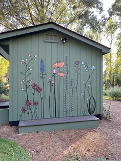 a green shed with flowers painted on the side