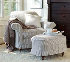 a chair and ottoman in front of a window with white carpeted flooring next to a dresser