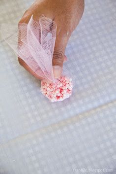 a person holding something in their hand with pink and white sprinkles on it