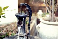 an old water faucet sitting on top of a table next to a potted plant