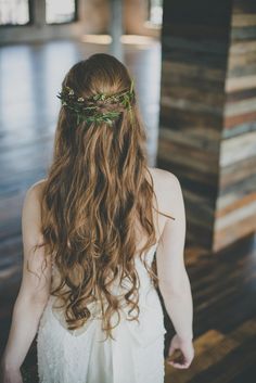 a woman with long brown hair wearing a wreath of flowers on her head and dress