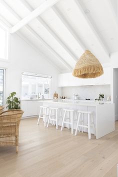 an open kitchen with white walls and wooden flooring is pictured in this image, there are wicker stools on the counter