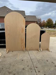 three unfinished wooden doors sitting in front of a black truck on the street next to a house