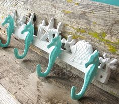 three seahorse hooks hang on a wooden plank with blue paint and white cast iron