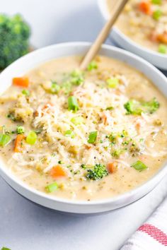 two bowls of soup with broccoli, carrots and cheese