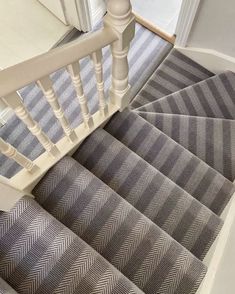 the stairs in this house are lined with grey and white herringbone rugs,