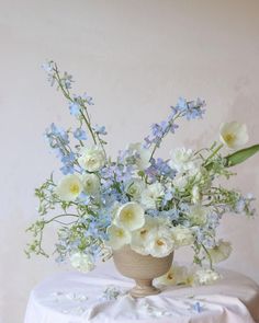 a vase filled with white and blue flowers on top of a table