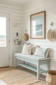 a bench sitting in the middle of a living room next to a door with hats hanging on it