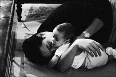 a woman holding a baby in her arms while laying on the ground next to stairs