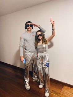 a man and woman in silver outfits standing next to each other on a wooden floor