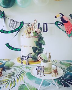 a cake with zebras, giraffes and palm leaves on the table