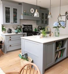 a kitchen with gray cabinets and white counter tops, wooden floors, and hanging lights