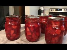 several jars filled with pickles sitting on top of a white table cloth next to an oven