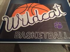 a sign that says wildcats basketball with a dog paw on the front and an orange ball in the middle